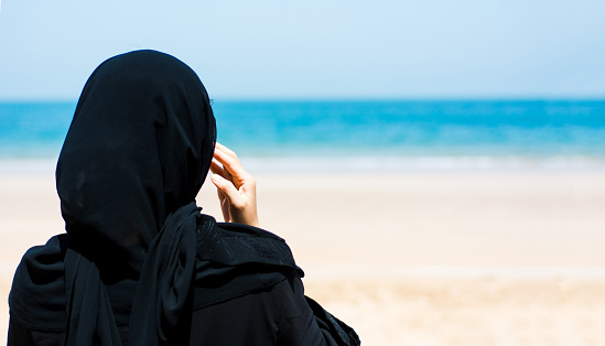 Muslim woman on the sunny beach back view