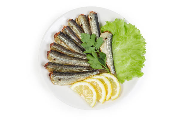 istock Smoked sprats with lemon and greens on a white saucer 1141176241