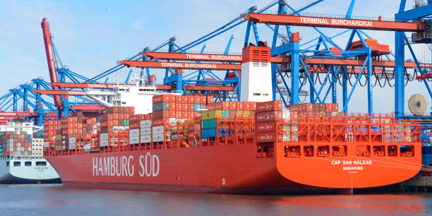 Cargo container ships with shipping containers docked at the container terminal in the port of Hamburg during a beautiful summer day.