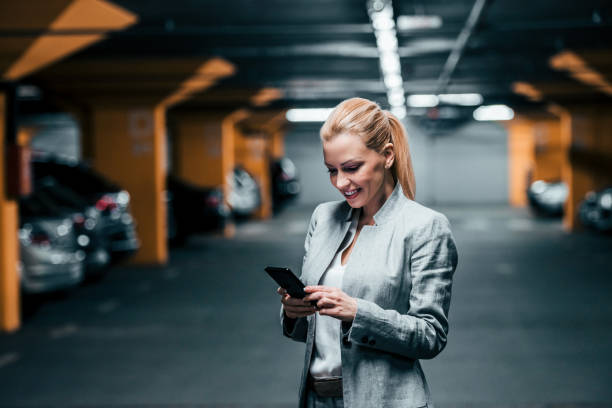 istock Blonde elegant woman using smartphone in parking garage. 1141179528