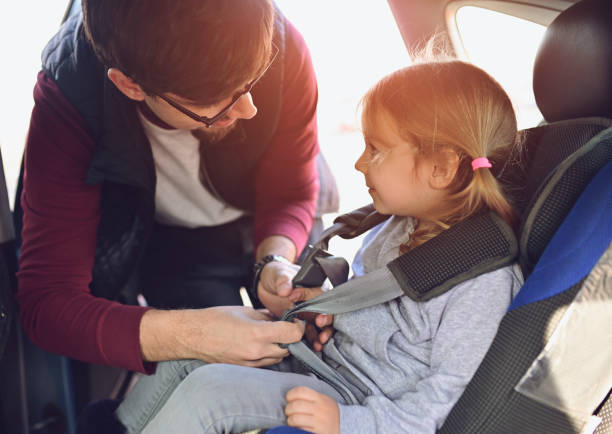 Safety first, father puts child in car seat