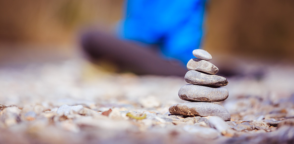 Cairn on a pebble beach, meditating woman in the background