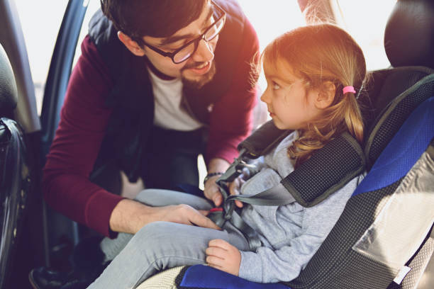 istock Safety first, father puts child in car seat 1141181932