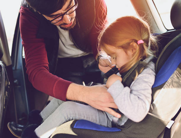 istock Safety first, father puts child in car seat 1141182444