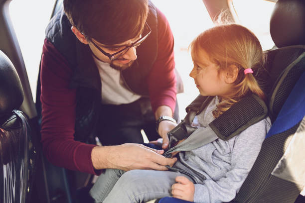 istock Safety first, father puts child in car seat 1141182600