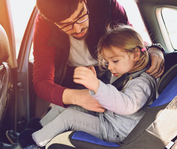 istock Safety first, father puts child in car seat 1141183417