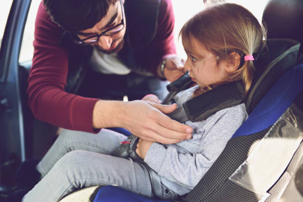istock Safety first, father puts child in car seat 1141183583