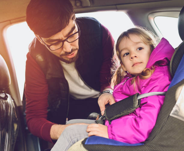 istock Safety first, father puts child in car seat 1141183753