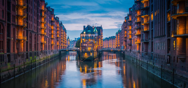 Warm lamplight illuminating the historic UNESCO World Heritage Site of Speicherstadt, City of Warehouses, district in the heart of Hamburg, Germany’s vibrant second city.