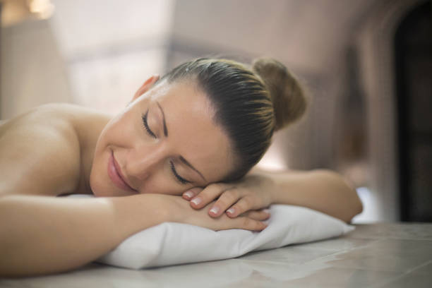 Young woman relaxing at the spa lying on the bed - beauty concepts