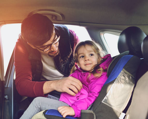 istock Safety first, father puts child in car seat 1141184012