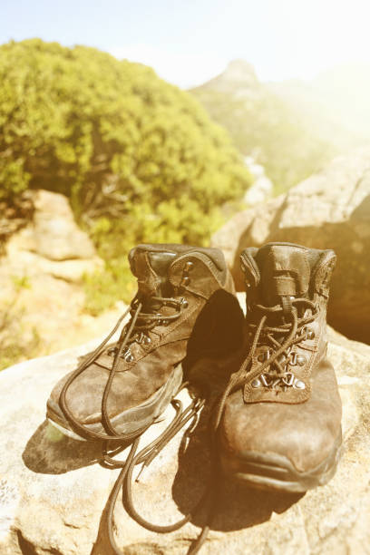 istock Worn old hiking boots on sunny mountain trail 1141187716