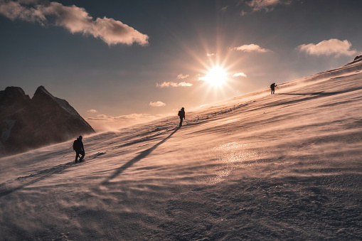 Mountaineers climbing in blizzard on snowy hill at sunset. Ryten mountain