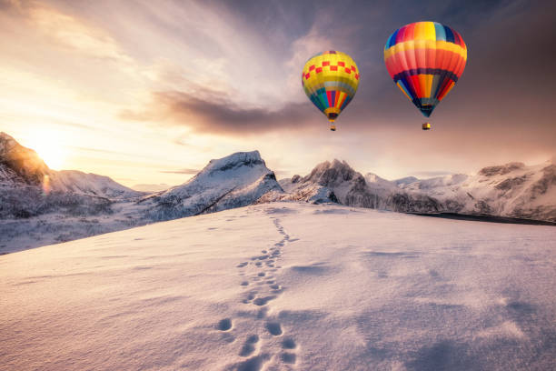 Hot air balloons flying on snowy mountain with footprint on peak Hot air balloons flying on snowy mountain with footprint on peak at sunrise senja island photos stock pictures, royalty-free photos & images