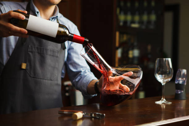 сомелье наливает вино в бокал из декантера. официант-�мужчина - wine decanter red restaurant стоковые фото и изображения