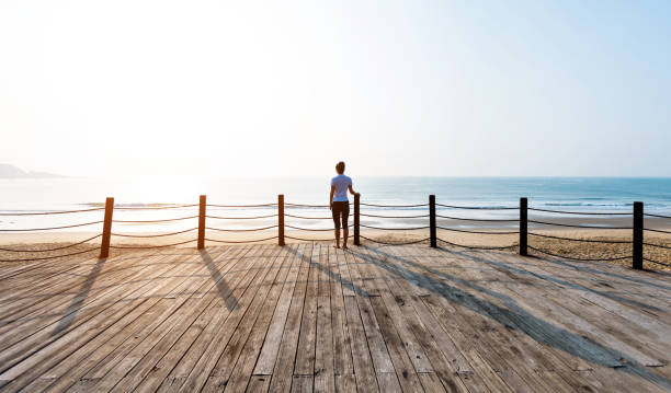 istock Woman standing on boardwalk at the beach 1141196085