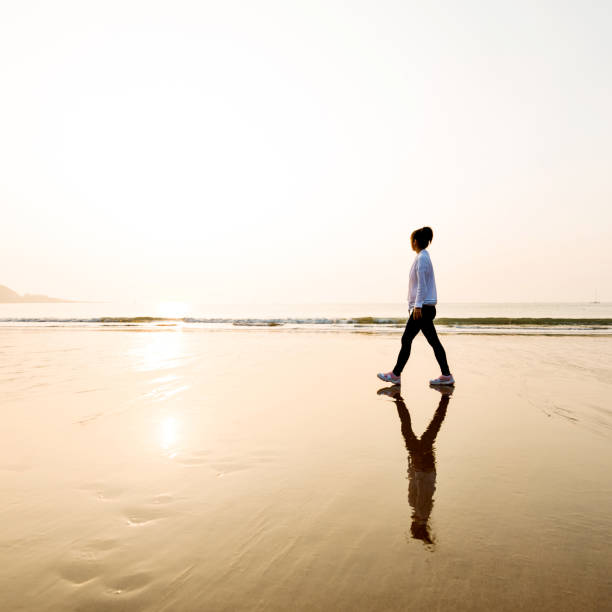 istock Woman walking on the beach at sunset 1141197089