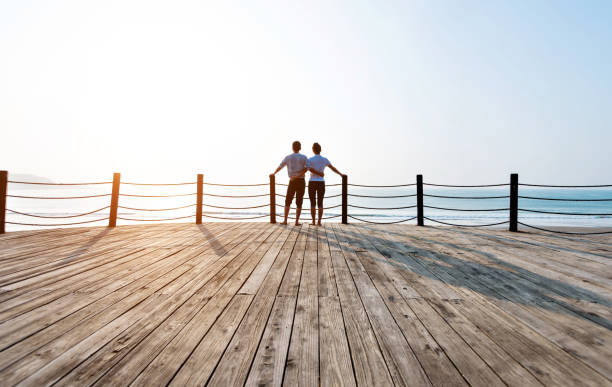 istock Couple standing on boardwalk at the beach 1141197250