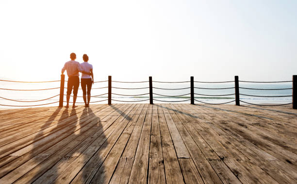 istock Couple standing on boardwalk at the beach 1141197279