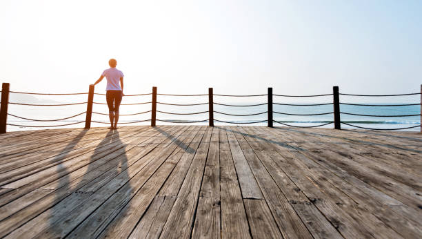 istock Woman standing on boardwalk at the beach 1141197340