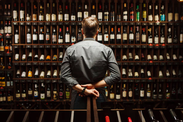 camarero en la bodega llena de botellas con exquisitas bebidas - wine cellar fotografías e imágenes de stock