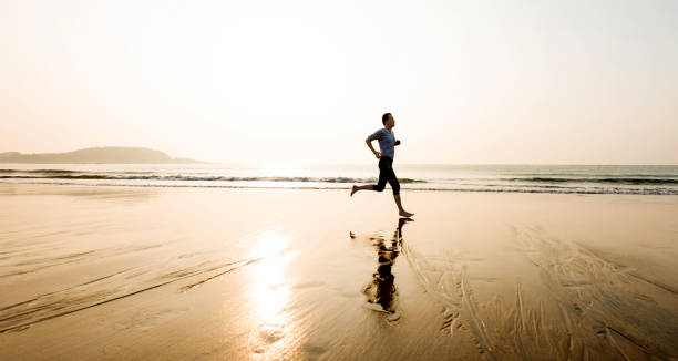 Man running on the beach at sunset Man running on the beach at sunset. sportsman professional sport side view horizontal stock pictures, royalty-free photos & images