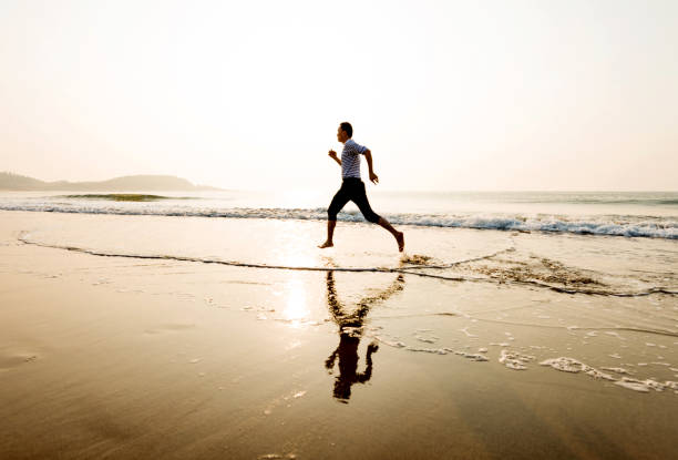 istock Man running on the beach at sunset 1141198249