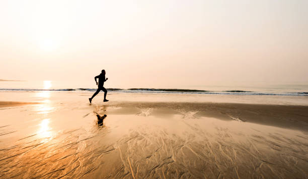istock Man running on the beach at sunset 1141198252