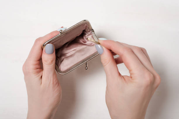 istock Hand puts a coin in an empty open metal purse on a light background 1141199015