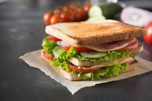 istock Sandwich with bacon, tomato, onion, salad on black. Close up. 1141199246