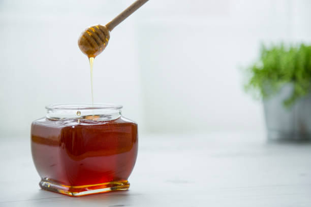 istock Pouring honey into jar of honey 1141199258