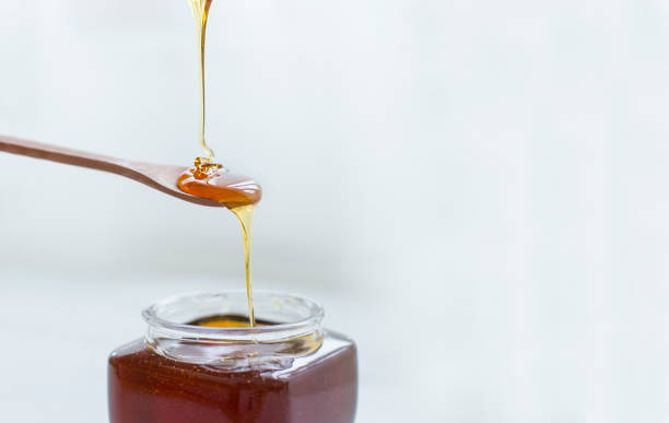 istock Pouring honey into jar of honey 1141199441