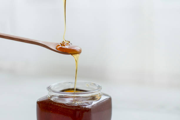 istock Pouring honey into jar of honey 1141199564
