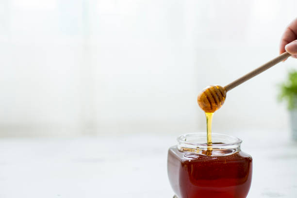 istock Pouring honey into jar of honey 1141201104