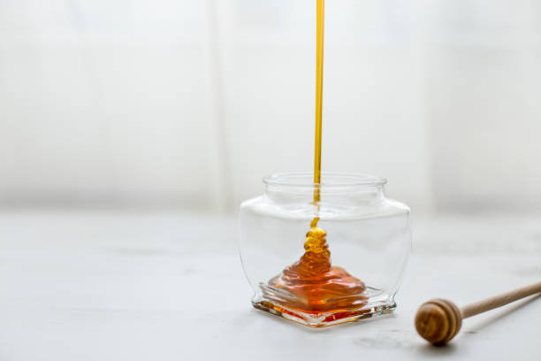 istock Pouring honey into jar of honey 1141201177