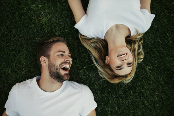 istock Hilarious laughing pair locating on green grass 1141201424