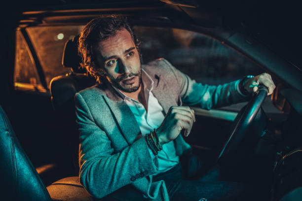 istock Modern man driving a car in city at night 1141201773