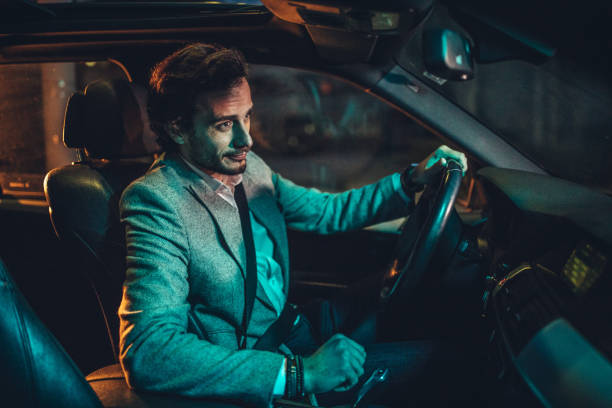 istock Modern man driving a car in city at night 1141201827