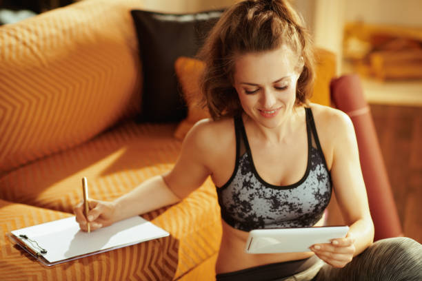 sports woman taking notes while watching fitness tutorial