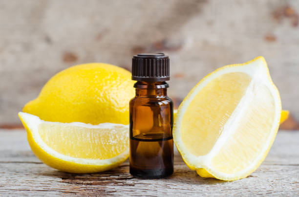오래 된 나무 배경에 에센셜 레몬 오일의 작은 병. 아로마 테라피, 스파와 한방 의학 성분. 복사 공간. - infused oil 이미지 뉴스 사진 이미지