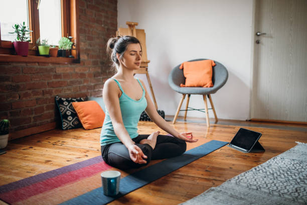 Meditation and Spirituality at Home Young woman relaxing herself practicing meditation at her home exercise room photos stock pictures, royalty-free photos & images