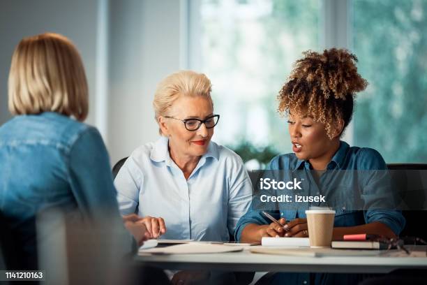 Businesswoman Talking With Executives At Desk Stock Photo - Download Image Now - Mature Women, Role Model, 35-39 Years