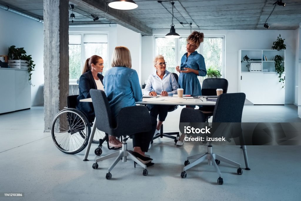 Expertise sharing ideas with colleagues in office Pregnant expertise sharing business ideas with colleagues in office. Confident professionals are brainstorming at desk. They are working together. Office Stock Photo