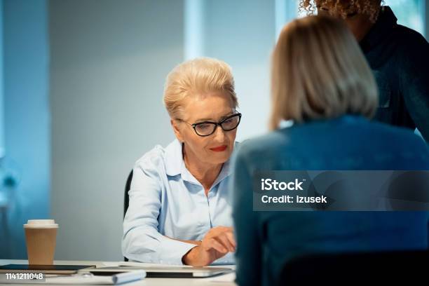 Senior Woman Working With Colleagues In New Office Stock Photo - Download Image Now - 35-39 Years, 40-44 Years, 70-79 Years