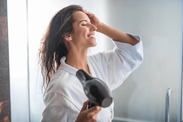 istock Cheerful female drying hair with gadget 1141213166