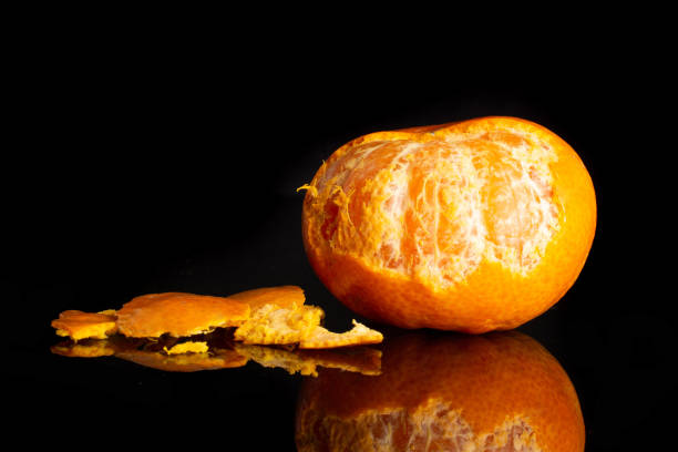 istock Mandarine with a leaf isolated on black glass 1141213287