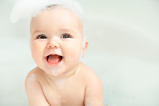 Una niña se Besta en un baño con espuma y jabón burbujas photo