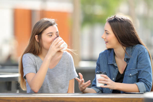 istock Two casual friends talking and drinking coffee in a park 1141215109