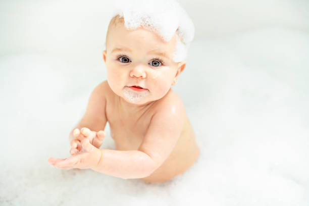una niña se besta en un baño con espuma y jabón burbujas - shower child shampoo washing fotografías e imágenes de stock