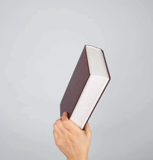 istock hand holds a closed book in hardcover 1141221471